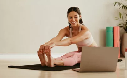 Frau macht Yoga vor dem Laptop